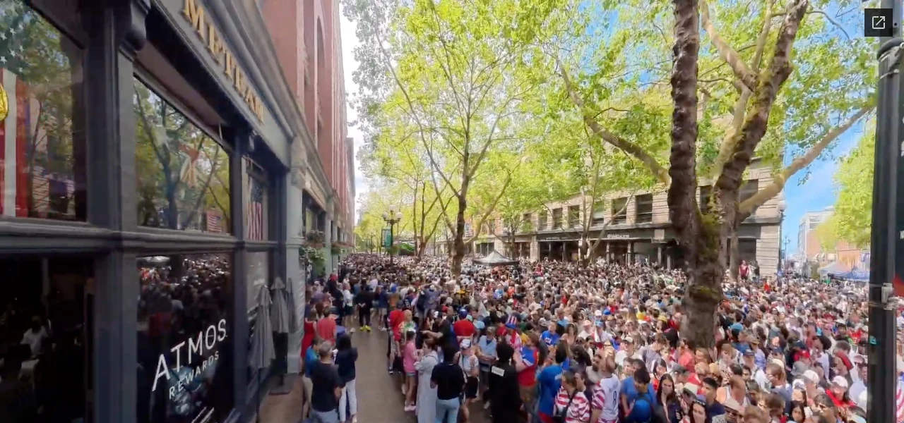 Atmos Rewards sign on the left of HOMETEAM, with a crowd extending through the surrounding Seattle watch-party space.